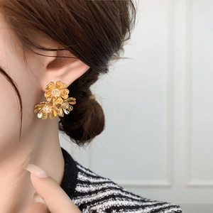 Detailed close-up of golden vintage C-shaped earrings with layered floral petal texture