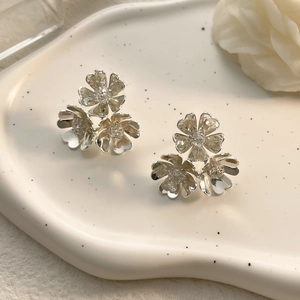 Detailed view of silver triple floral stud earrings with tiny zircons on a white ceramic tray