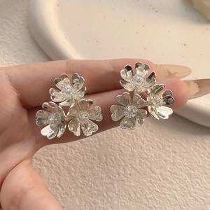 Macro detail of silver floral cluster earrings with three petal flowers and zircons