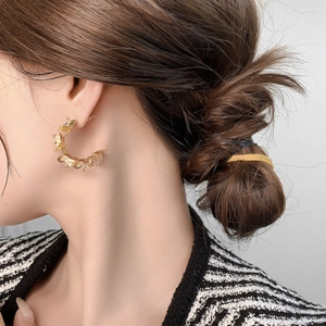Detail of C-shaped gold butterfly earrings with zircons worn by a model