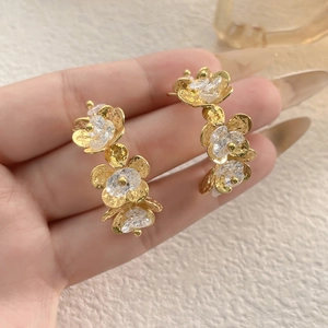 Detailed view of gold petal earrings with clear crystals and 3-flower drop design