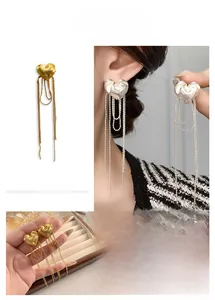 Detail of gold heart stud earrings with long chain tassels and matte brushed finish