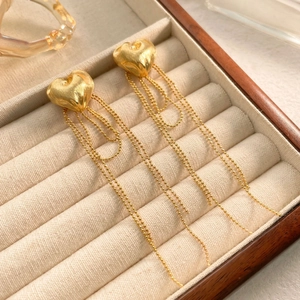 Detail of gold-plated heart studs with dangling beaded chain tassels on velvet display