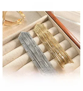Détail de boucles d'oreilles pampilles or et argent avec chaînes fines et strass brillants