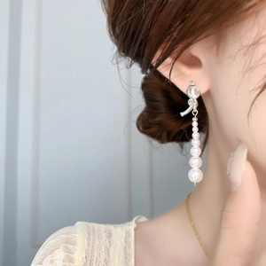Boucles d'oreilles nœud en argent avec perles blanches élégantes portées sur l'oreille