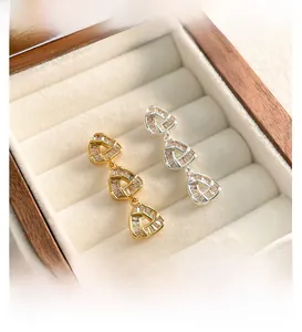 Macro shot of geometric triple triangle drop earrings with cubic zirconia in a jewelry box
