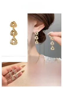 Detailed view of gold earrings with hollow triangle design and sparkling pavé zircon stones