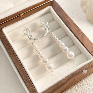 Vue macro détaillée de boucles d'oreilles nœud asymétriques avec perles en dégradé