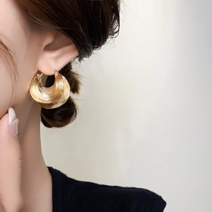 Detailed view of vintage gold hoop earrings with multi-layered leaf texture on ear