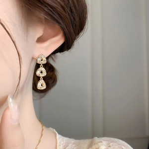 Detailed view of triple triangle drop earrings with cubic zirconia in gold plating