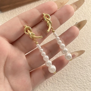 Vue détaillée de longues boucles d'oreilles perles avec nœud doré et dégradé de perles