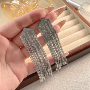 Détail de boucles d'oreilles pendantes argentées avec de fins cristaux scintillants