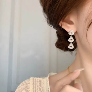 Close-up of triple layered silver triangle earrings with sparkling zircon crystals