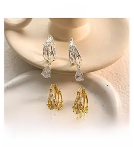 Macro view of water drop earrings in gold and silver with hollow butterfly details