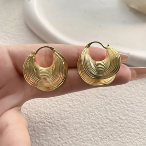 Macro detail of gold layered spiral leaf texture earrings with brushed metal finish