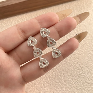 Close-up of silver geometric earrings with three stacked triangle zircons for women