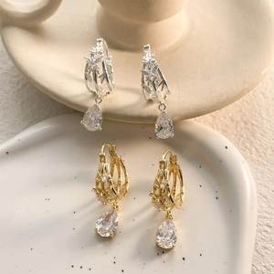 Detail of luxury teardrop earrings with hollow metal weave and pear-cut clear stones