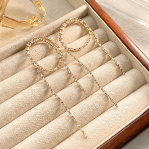 Detail of elegant gold tassel earrings with rectangular cubic zirconia on velvet