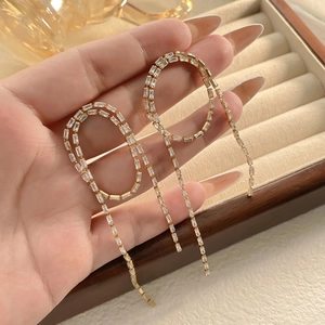 Macro view of gold-plated long tassel earrings with sparkling zircon gemstones