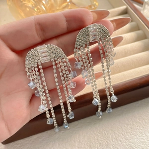 Elegant bridal tassel earrings with cubic zirconia and blue beads held by hand