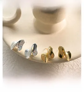 Detailed view of liquid metal gold and silver irregular earrings on ceramic display