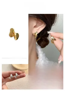 Detailed close-up of twisted irregular metal earrings in polished gold and silver finish