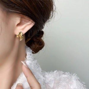 Close-up of golden abstract fluid twisted earrings on a model for a modern look