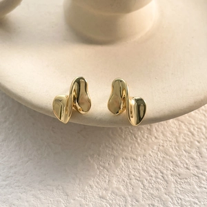 Close-up of elegant gold irregular twisted earrings with high polished surface detail
