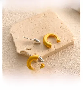 Detailed view of C-shaped earrings with gold matte and silver polished finish