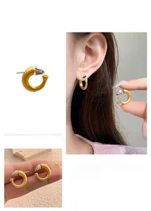 Detail of C-shaped matte gold earrings with silver arrow tips and earring closure