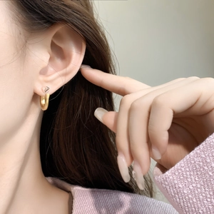 Macro shot of 18K gold plated C-shaped earrings on model for everyday wear fashion
