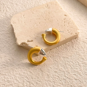 Macro detail of mixed-metal snake design earrings with matte gold and silver animal motifs