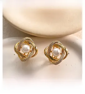 Vue macro de boucles d'oreilles géométriques plaquées or 18K avec micro-diamants et perles