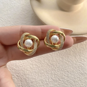 Gros plan de boucles d'oreilles géométriques dorées avec perle et cristaux brillants