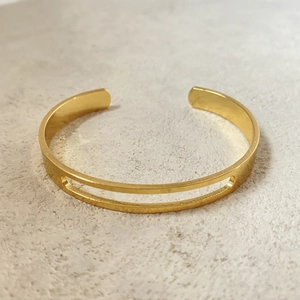 Elegant gold-plated open cuff bracelet with dual hollow stripes on stone background