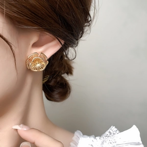 Gros plan d'une boucle d'oreille tournesol vintage en laiton plaqué or 18 carats sur modèle