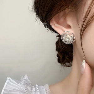 Détail d'un clou d'oreille fleur argentée avec texture métallique sur l'oreille