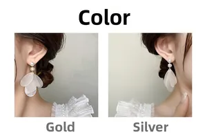 Detail of elegant gold and silver petal tassel earrings with pearls on white lace dress