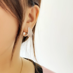 Close-up of sparkling full-diamond heart earrings worn on ear with rose gold finish