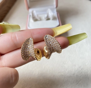 Macro shot of gold-plated fan-shaped earrings with micro-pave shimmering crystal rhinestones