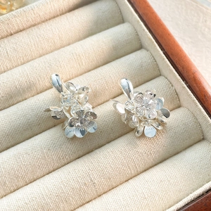 Détail macro de boucles d'oreilles fleur argentées aux pétales multicouches sur velours