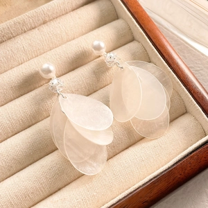 Detail view of white pearl tassel earrings with translucent petal drops in a wooden box