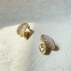 Macro view of gold twisting heart earrings with pavé sparkling white cubic zirconia