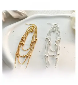 Detail of four-layer beaded tassel earrings in gold and silver finish on ceramic tray