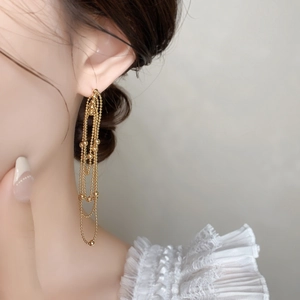 Close-up of elegant gold multi-layered bead chain tassel earrings worn by a model