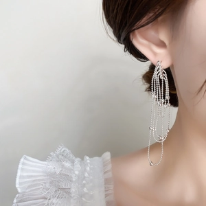 Detail of silver multi-layered bead chain tassel earrings worn on a model's ear