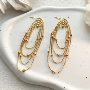 Detail of elegant gold layered bead tassel earrings on a ceramic display plate