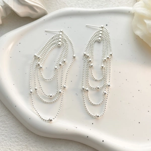 Macro shot of S925 sterling silver multi-layer bead chain fringe earrings on white tray