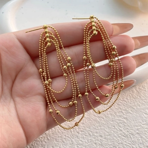 Close-up of elegant gold multi-layer beaded fringe earrings with long dangling tassels