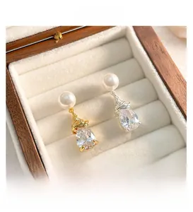 Détails macro des boucles d'oreilles en perles et zircons poire en or et argent